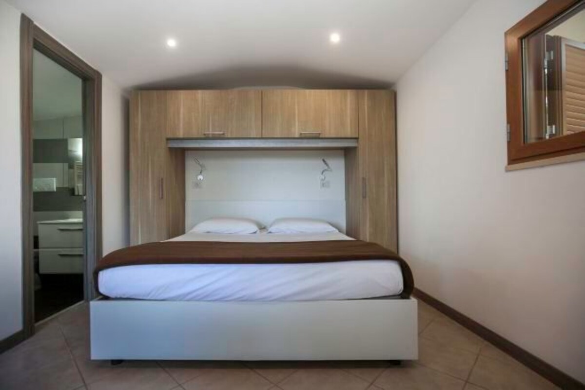 Un dormitorio con cama, cabecera de madera y ventana.