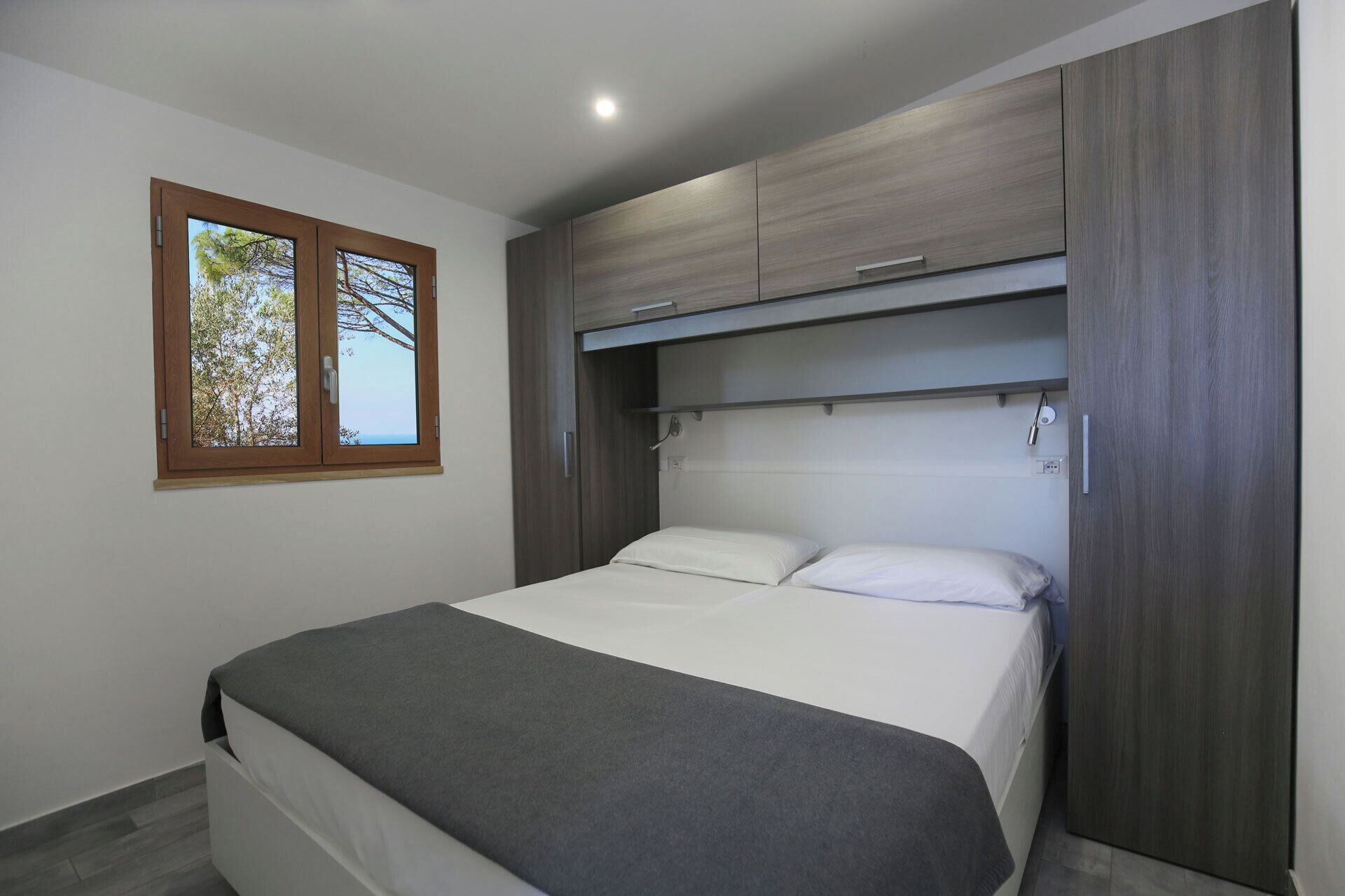 Une chambre à coucher avec un lit, une fenêtre et des armoires encastrées en bois.
