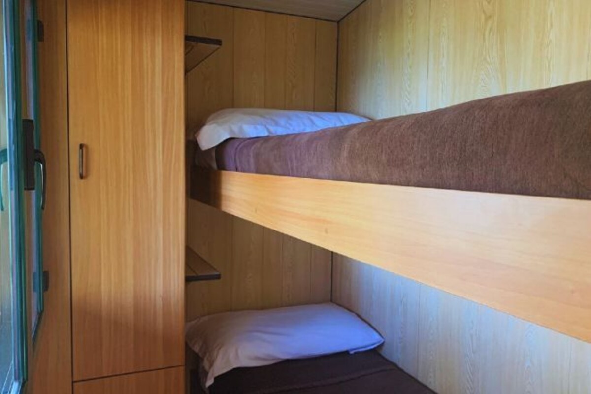 A bunk bed with a wooden wardrobe beside it.