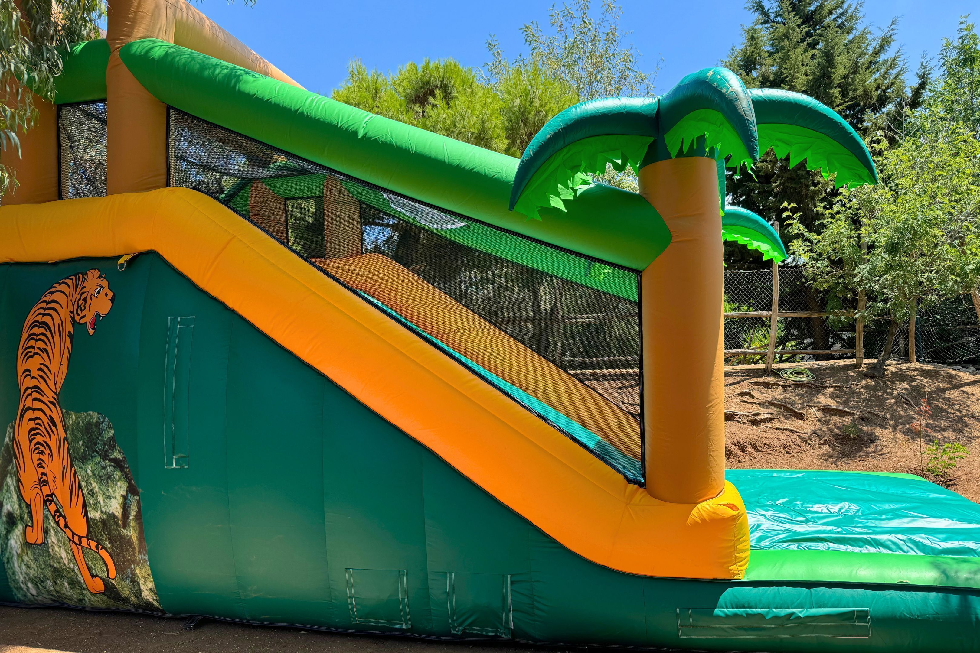 Una estructura inflable con un tobogán, una pared de escalar y una pequeña piscina.