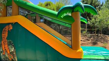 Una estructura inflable con un tobogán, una pared de escalar y una pequeña piscina.