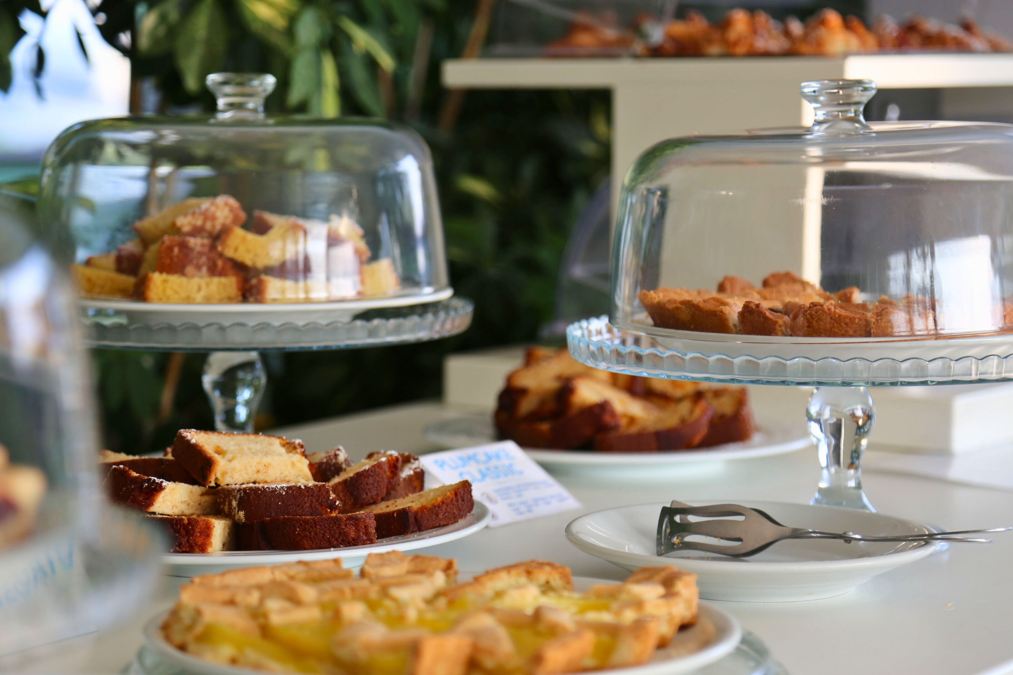 A buffet with various desserts under glass domes.