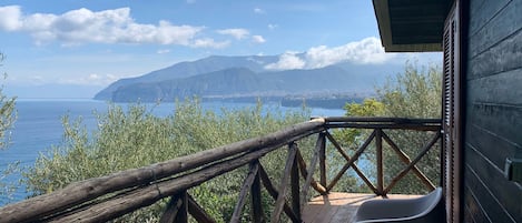 A wooden deck with a railing overlooking a body of water and distant mountains.