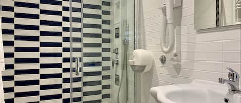 A bathroom with a glass-enclosed shower, a white sink, and a towel rack.