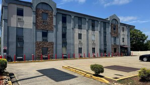 A multi-story building with a modern architectural design, featuring a mix of stone and concrete facades, large windows, and a parking area with yellow curbs and red bollards. - Gallus Stadium Park Inn, an Ascend Collection Hotel (Columbia)