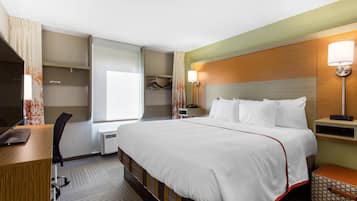 Een hotelkamer met een groot bed, een bureau, een stoel, een kledingkast en een raam met gordijnen.