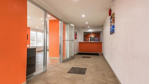 Un pasillo con puertas de cristal, una recepción y un cartel en la pared.
