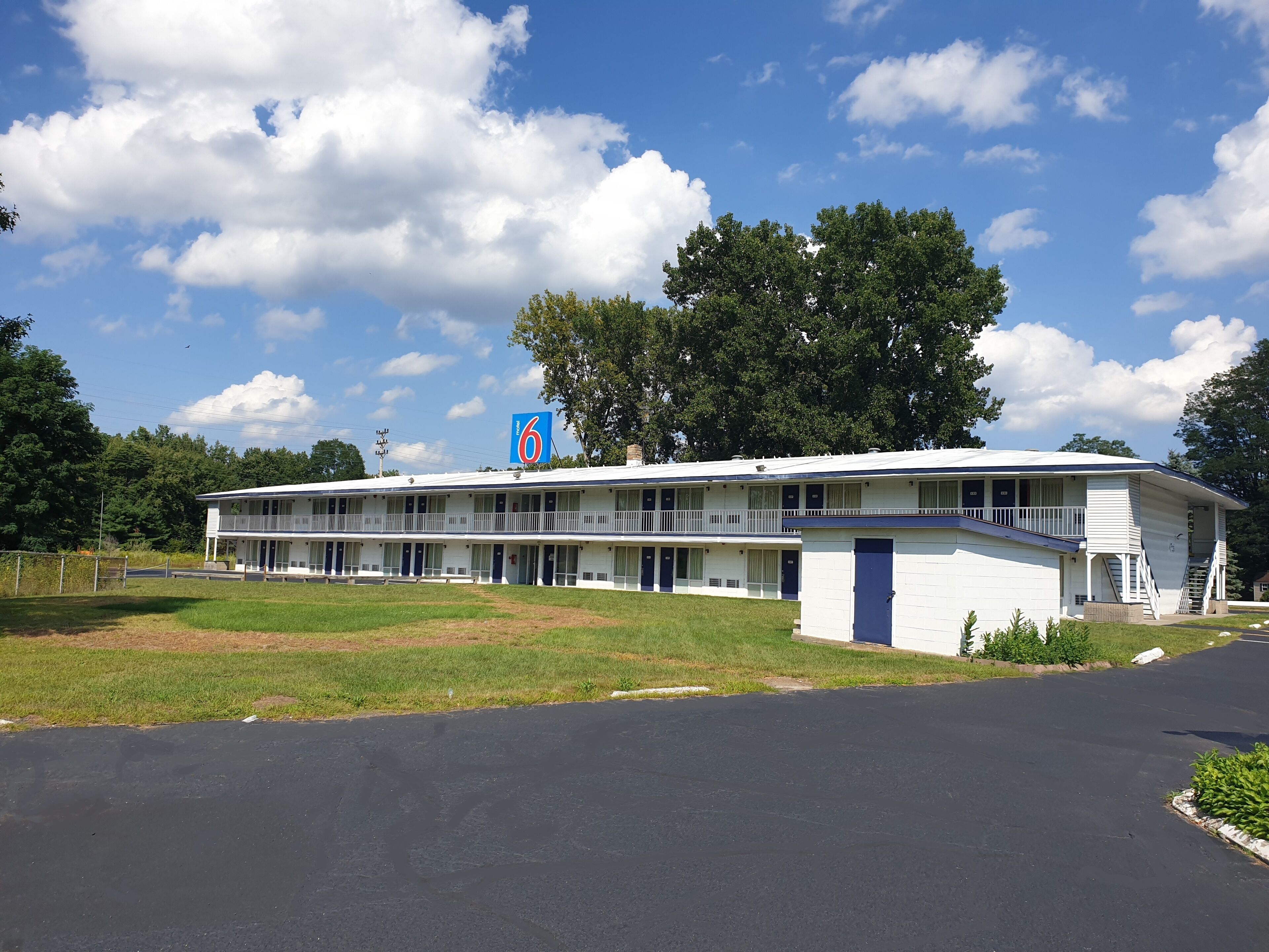 A motel with a two-story structure, multiple rooms, and a parking lot.