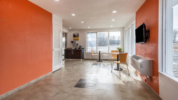 Un pasillo con una zona de cocina, una mesa de comedor con sillas y un televisor montado en la pared.