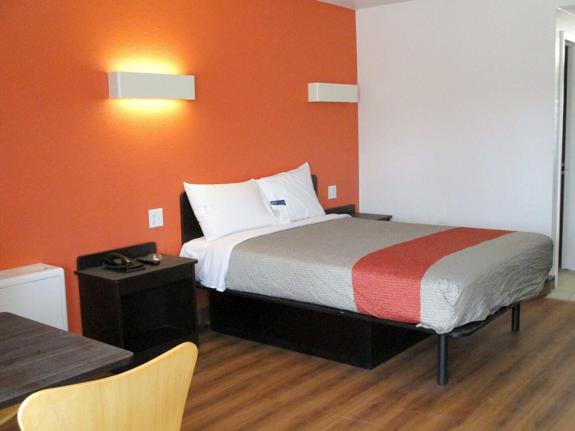 Una camera d'albergo con un letto, un comodino, una sedia e un tavolo.