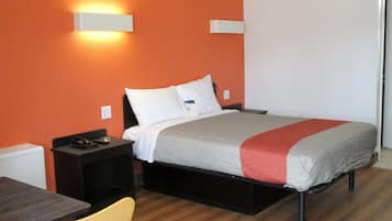 A hotel room with a bed, a nightstand, a chair, and a table.