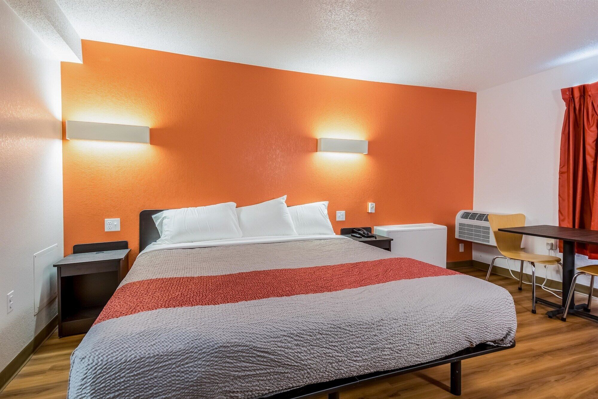 A hotel room with a bed, bedside tables, a desk, and a chair.