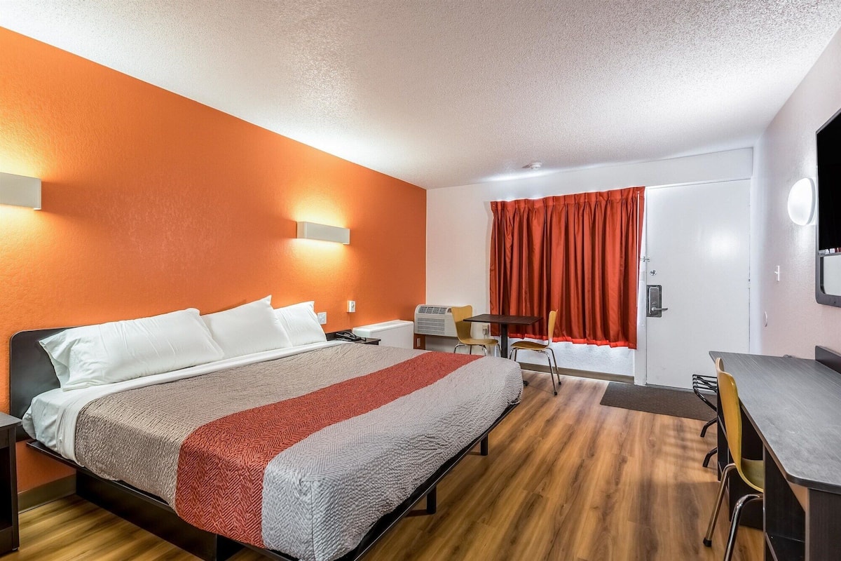 Une chambre d’hôtel avec un lit, un bureau et une chaise.