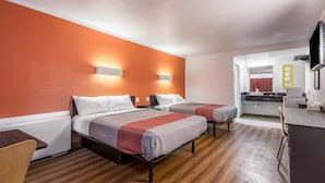 Habitación de hotel con dos camas, un escritorio, un espejo y un televisor.