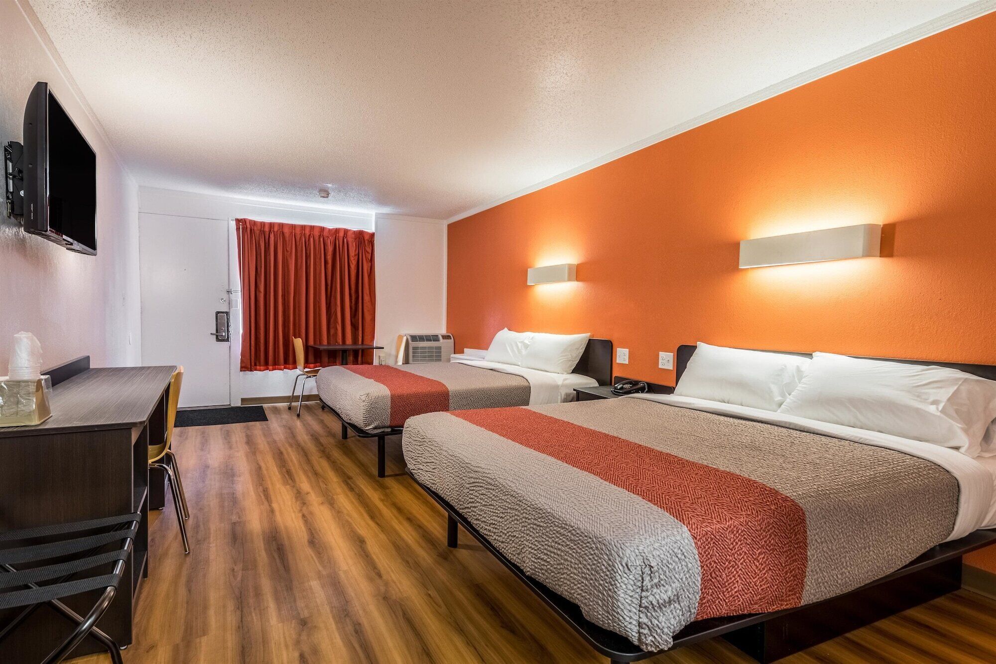 Hotellihuone, jossa on kaksi sänkyä, työpöytä, tuoli ja televisio.