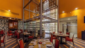 A restaurant with multiple dining tables, chairs, and a central glass display case. - Barceló Monterrey Valle (San Pedro Garza García)