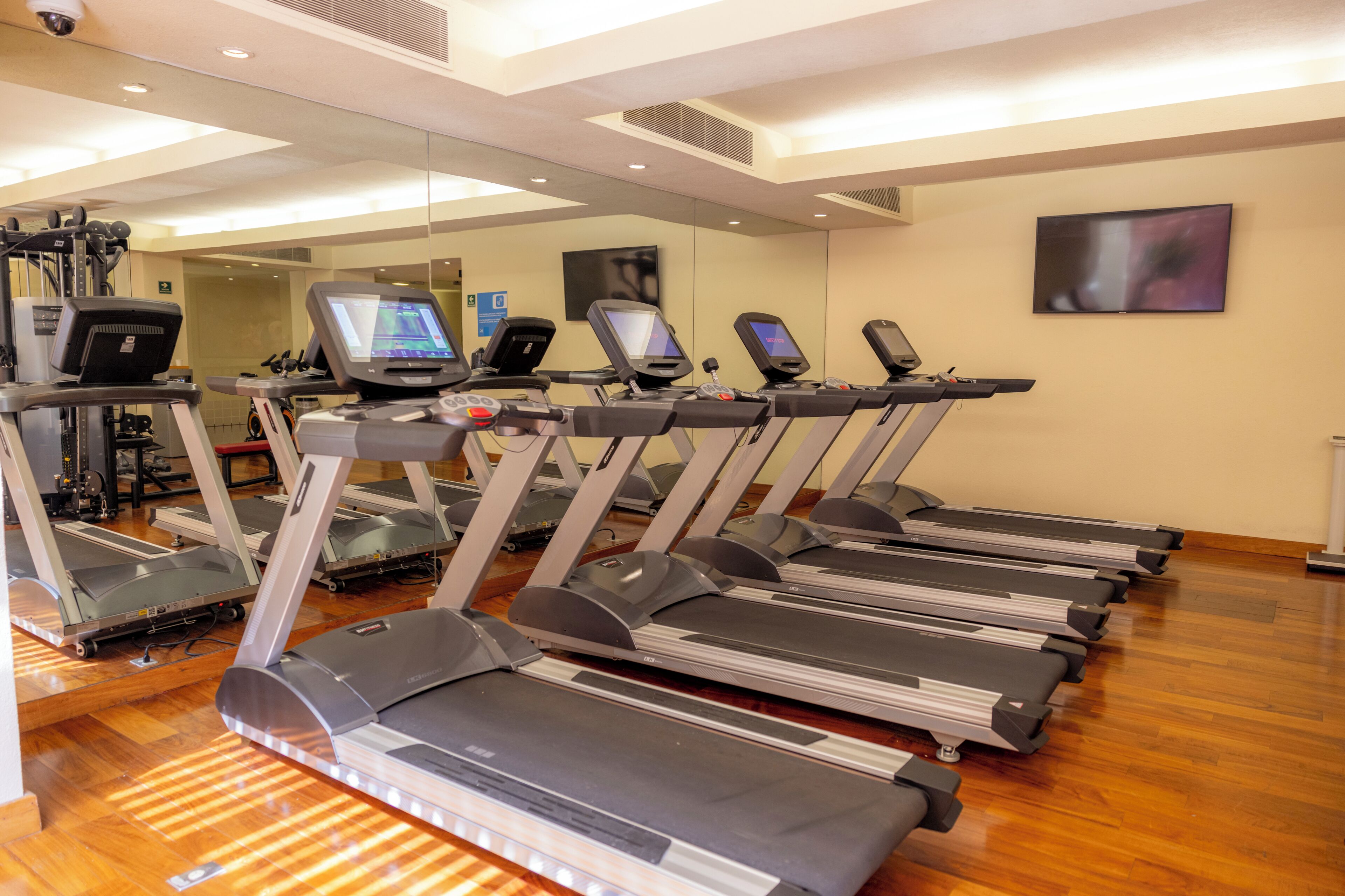 A gym with multiple treadmills, exercise equipment, and a mirrored wall.