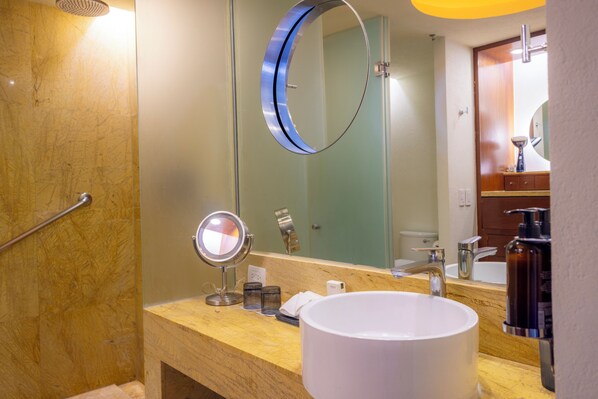 A bathroom with a round mirror, a sink, and a shower area.