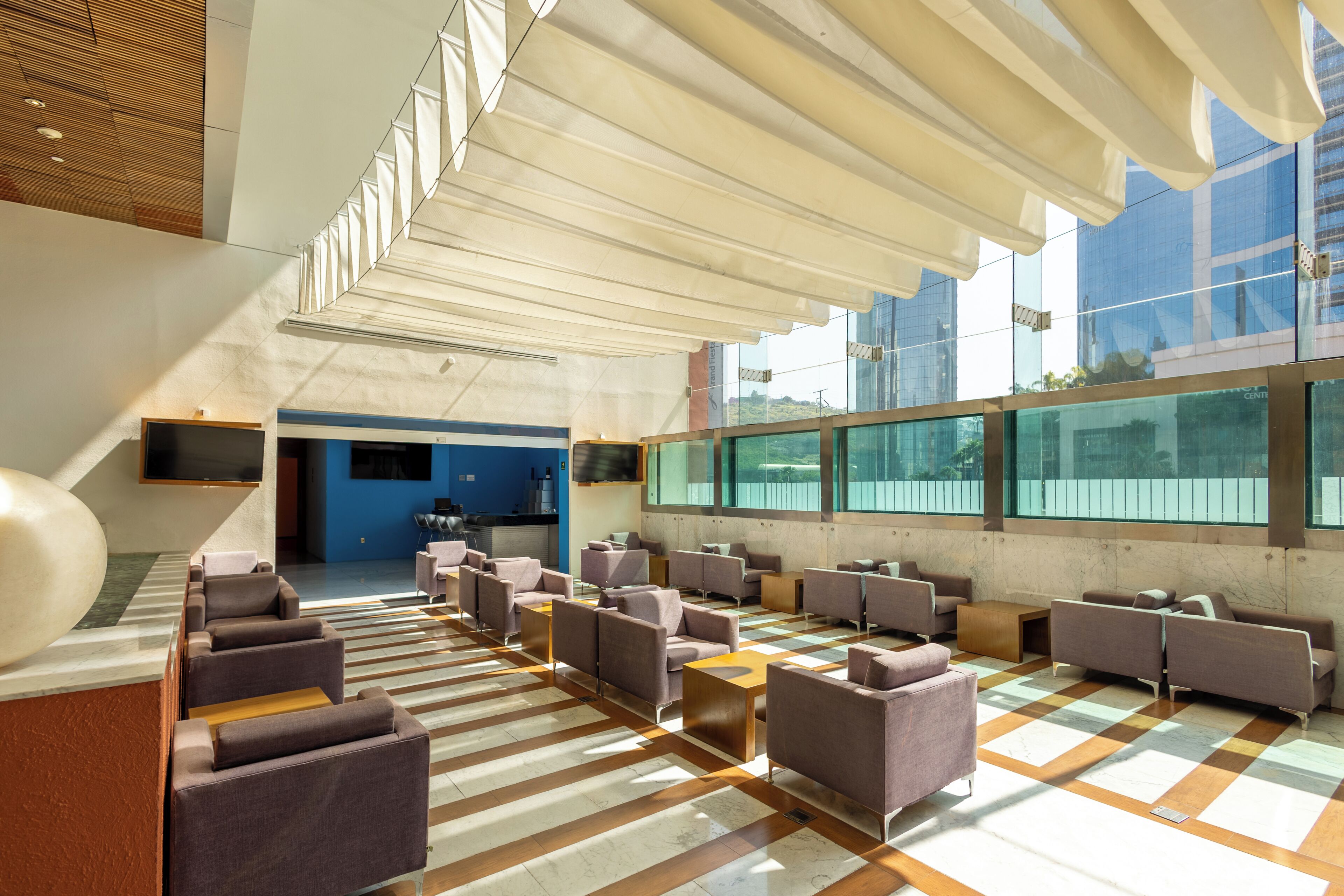 A spacious lobby with a checkered floor, multiple seating areas, and large windows offering views of the outside.