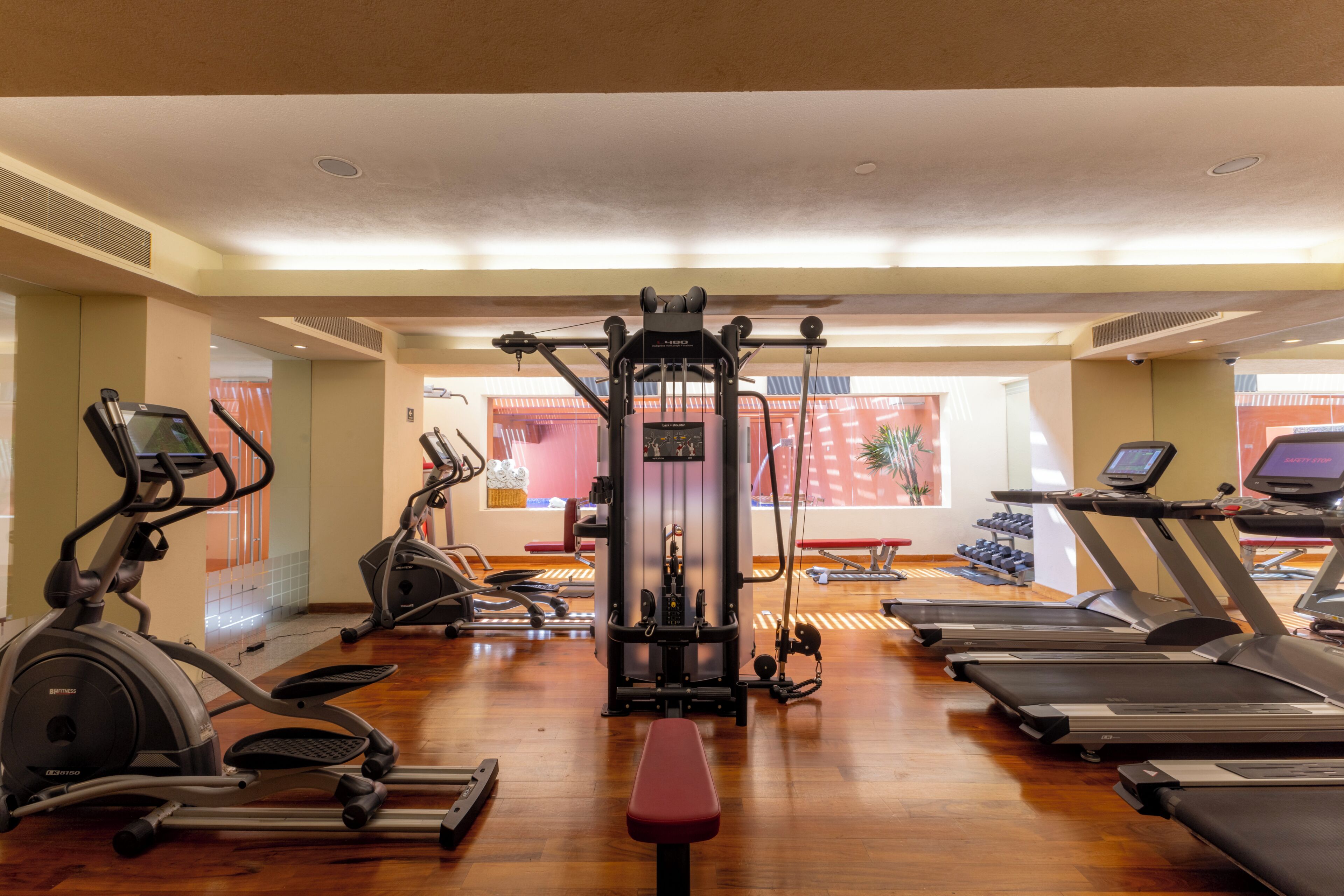Un gimnasio con cintas de correr, elípticas y máquinas de pesas.