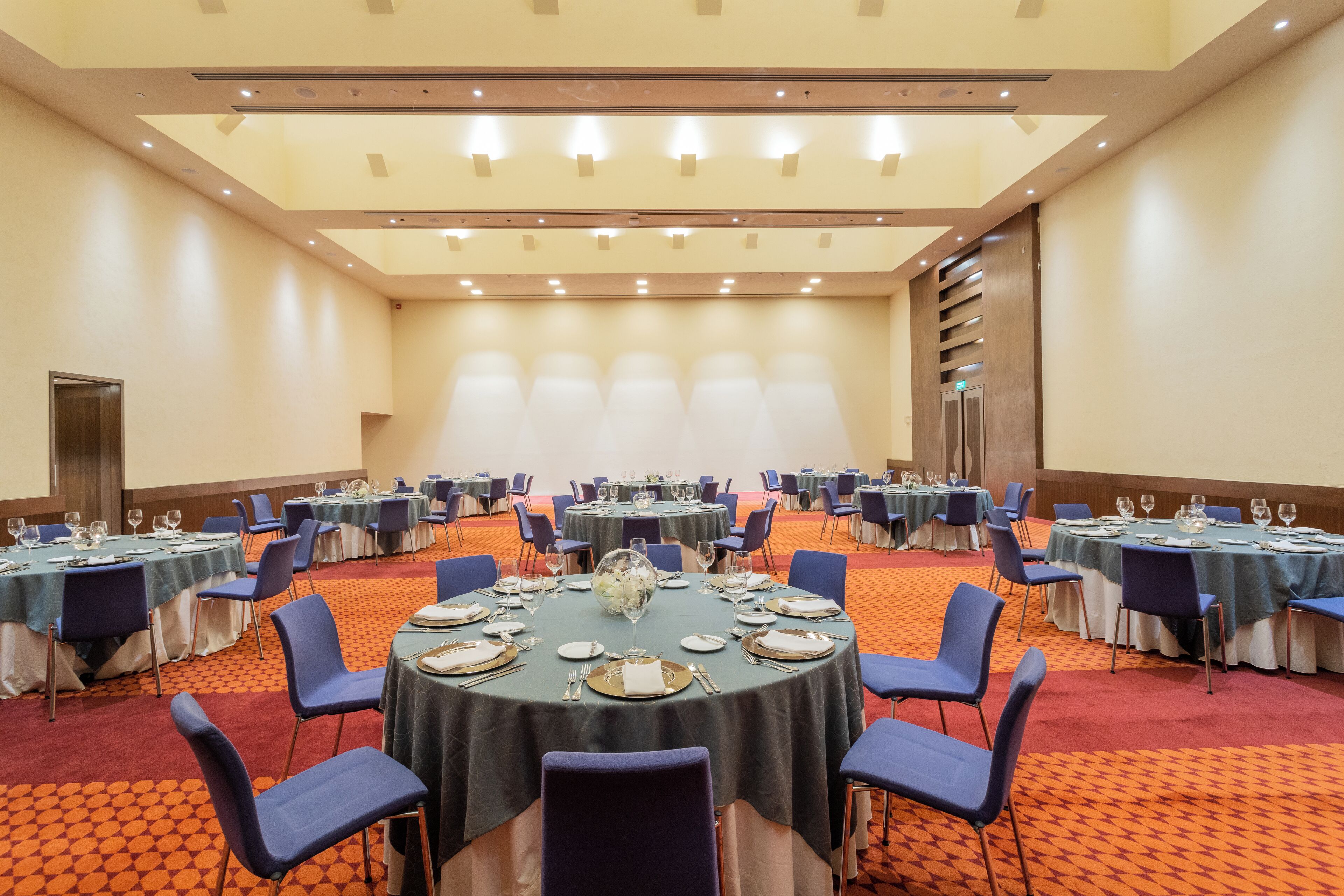 A conference room with round tables, blue chairs, and a carpeted floor.