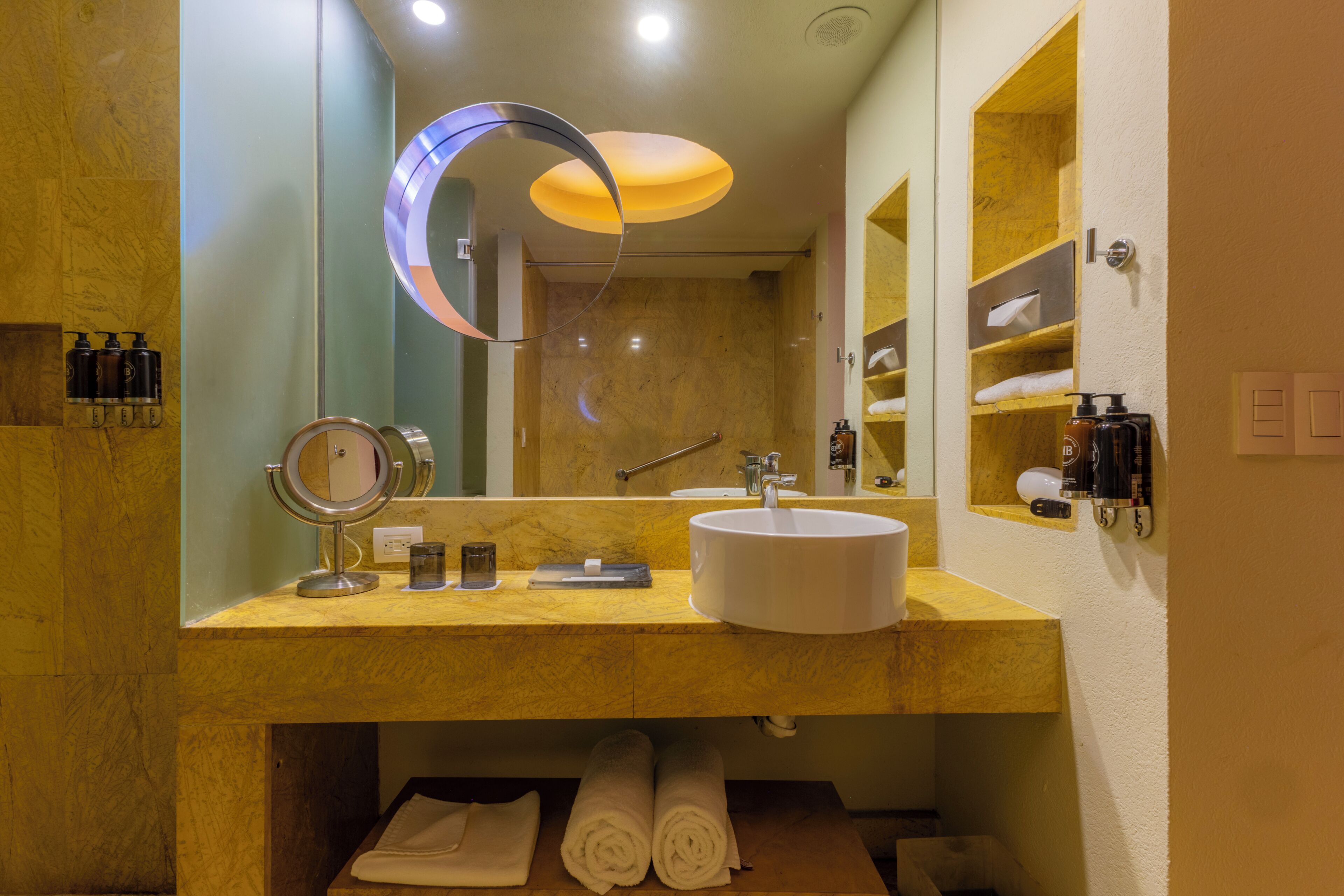 A bathroom with a sink, mirror, towel rack, and shelves.