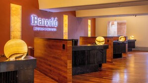 A hotel lobby with a reception desk, wooden paneling, and a neon sign. - Barceló Monterrey Valle (San Pedro Garza García)
