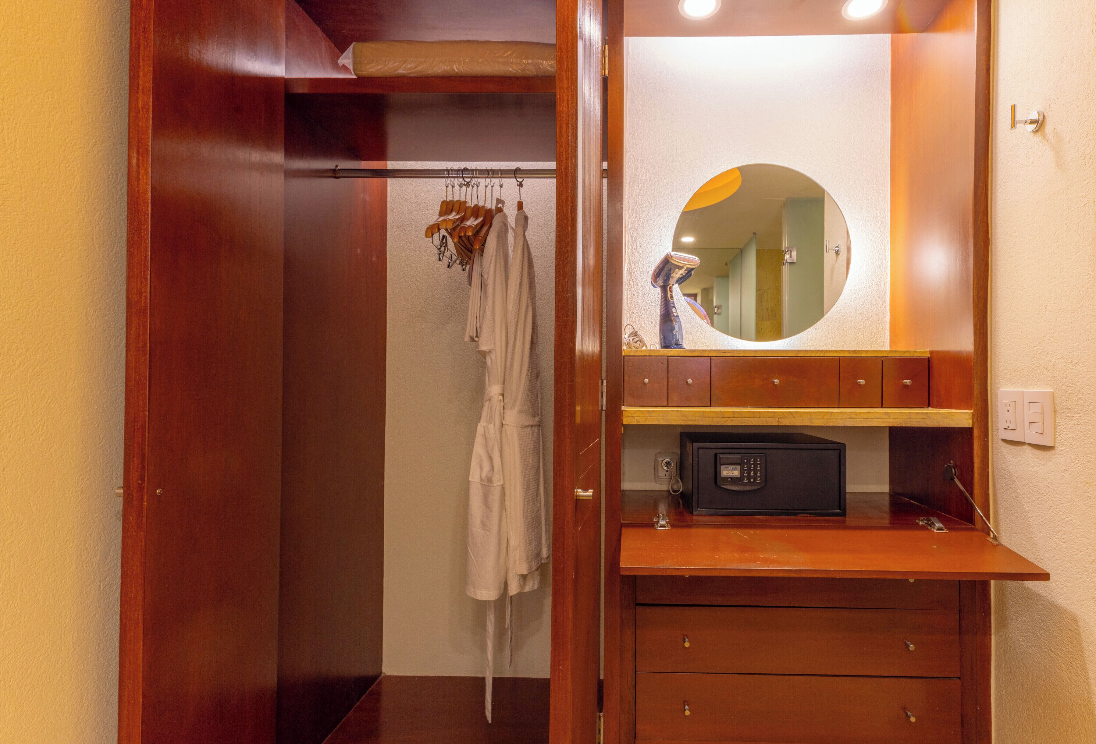 A bathroom with a wooden vanity, a round mirror, and a towel rack with robes.