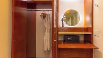 A bathroom with a wooden vanity, a round mirror, and a towel rack with robes.