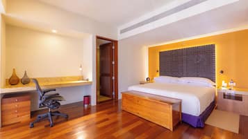 Un dormitorio moderno con una cama de madera, un escritorio con una silla, una mesita de noche y un baño visible a través de una puerta abierta.