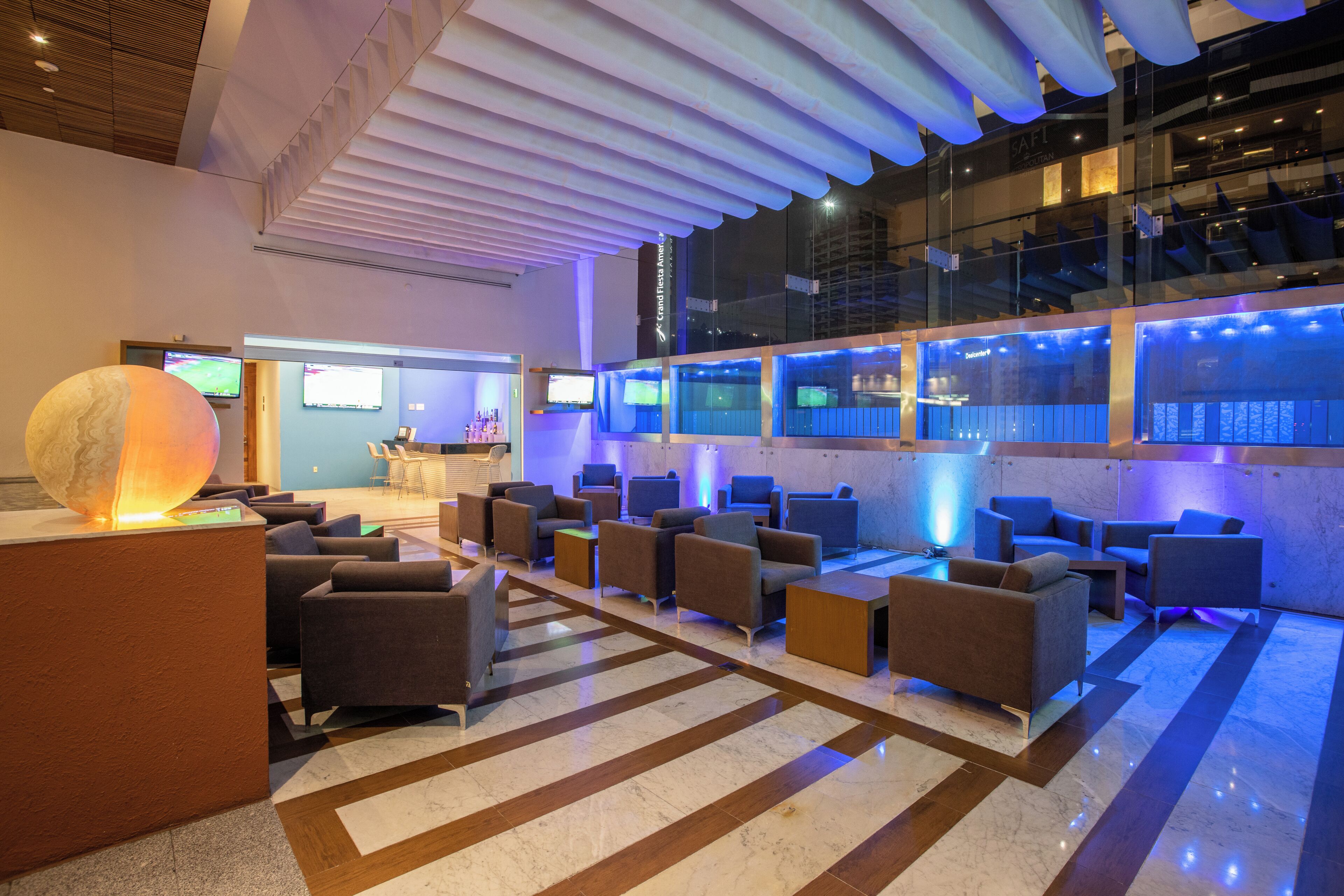 Un lobby moderno con zonas de estar, un mostrador de recepción y un gran globo decorativo.