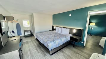 A modern hotel room with a large bed, bedside tables, a desk, and a mirror.