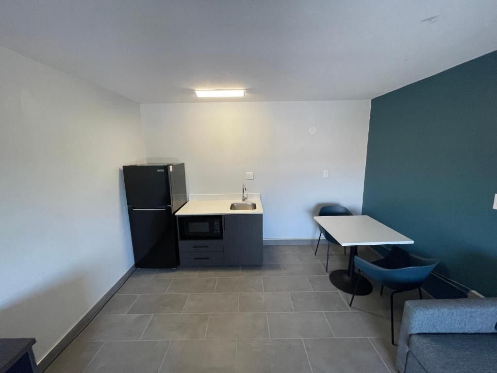 A compact kitchen with a refrigerator, sink, and a small dining area with a table and chairs.