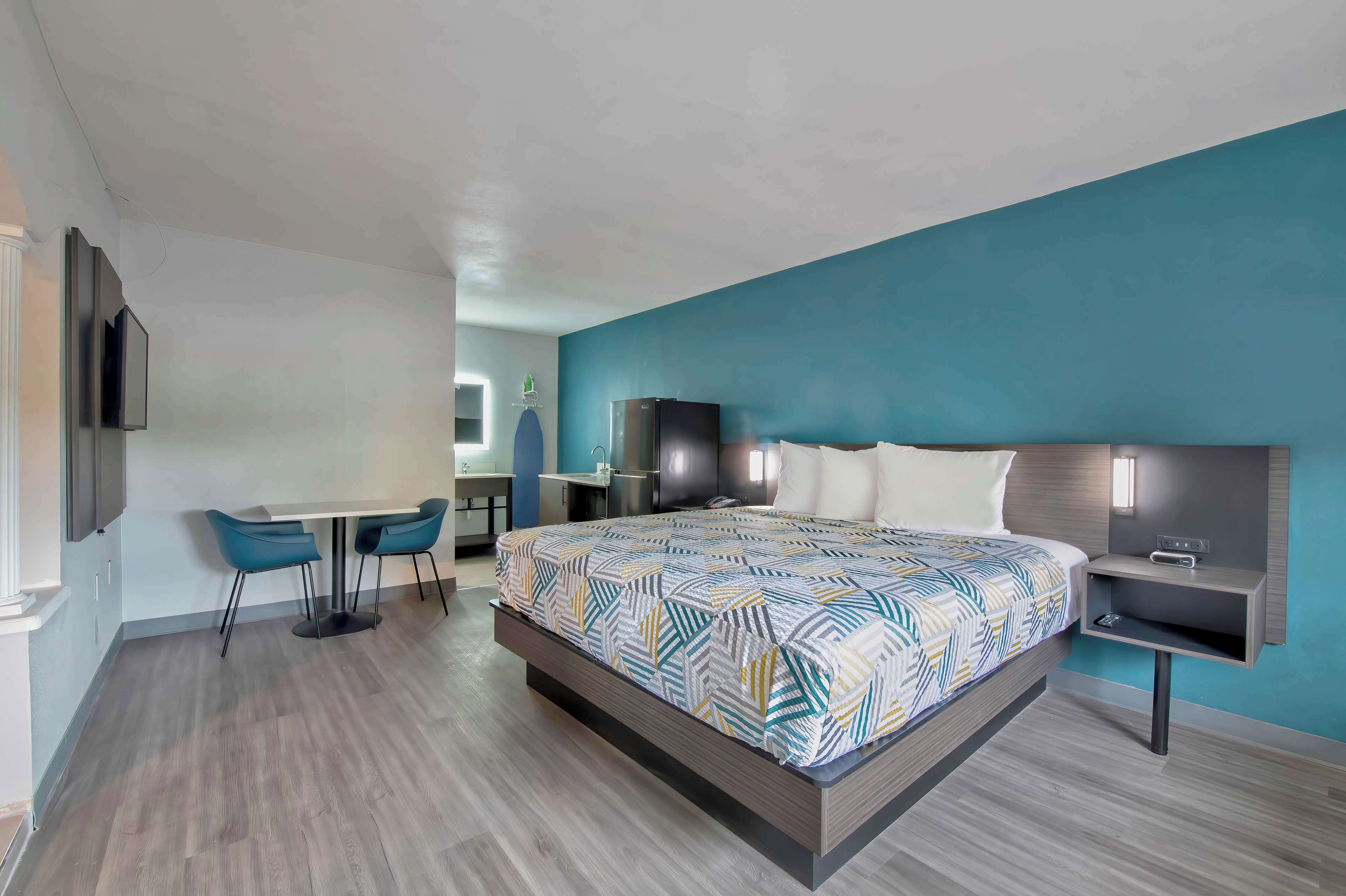 A modern hotel room with a large bed, a desk, and a chair.