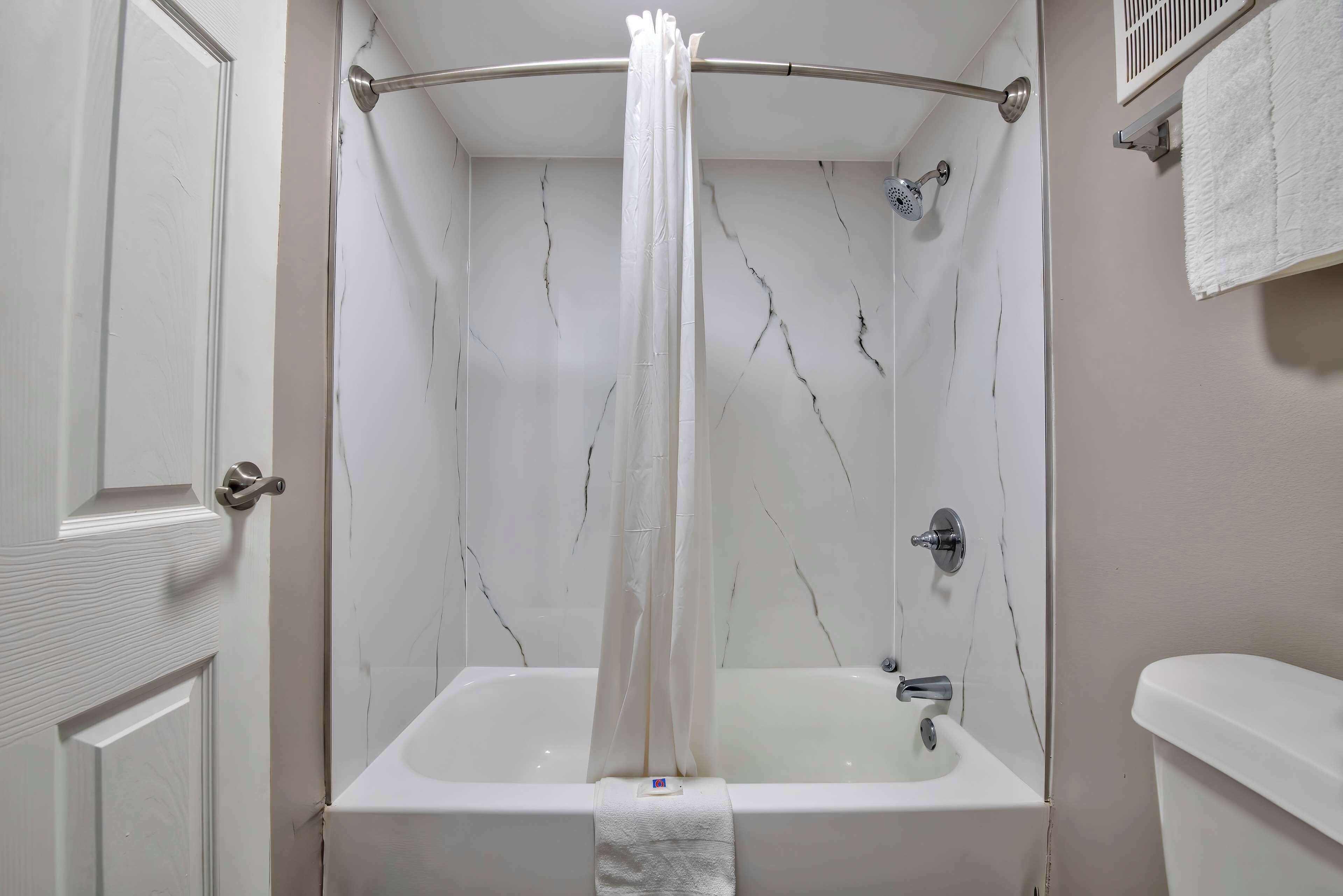 Un bagno con una vasca, un tendaggio doccia, un water e un portascopevoli.
