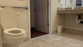 Un baño con inodoro, lavabo con espejo y una puerta que da a otra habitación.