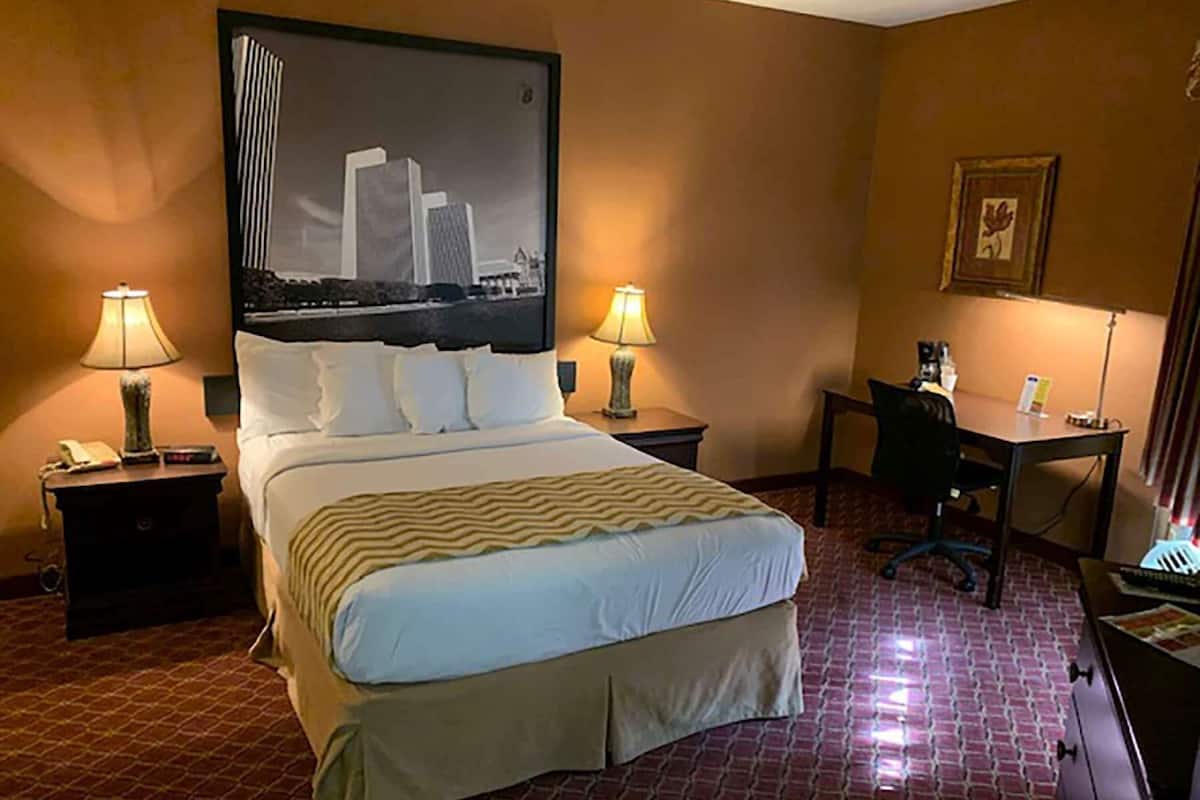A hotel room with a large bed, two bedside tables, a desk, and a chair.