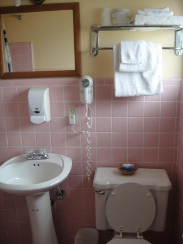Un baño con lavamanos, espejo, toallero y retrete.