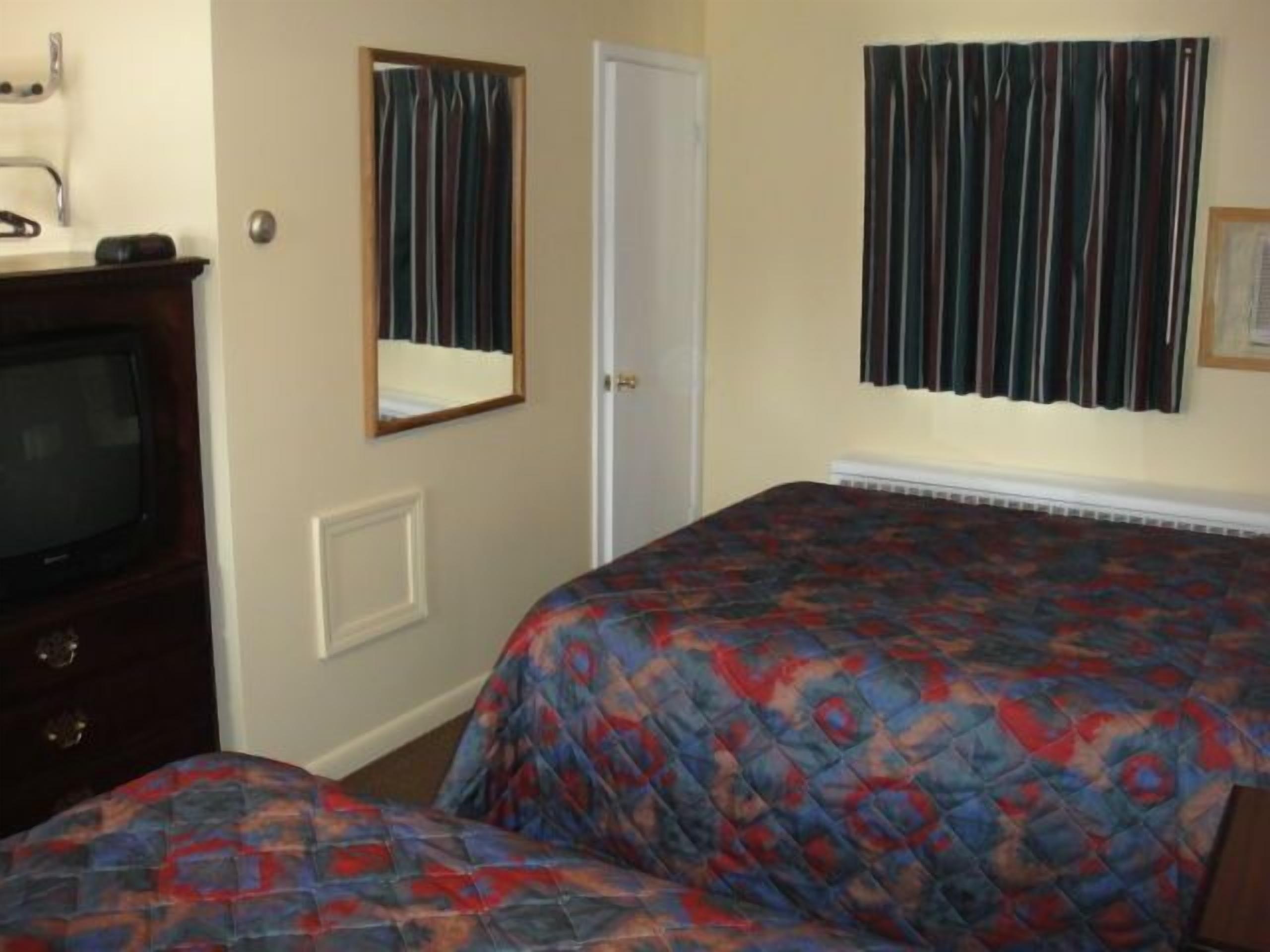 Un dormitorio con cama, televisión y una puerta.