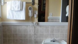 Un baño con inodoro, lavamanos y perchero para toallas.