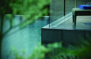 A modern outdoor seating area with a glass balustrade overlooking a body of water. - G Hotel Gurney (George Town)