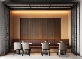 Un interior moderno con una larga banqueta, una mesa con sillas y un panel decorativo en la pared.
