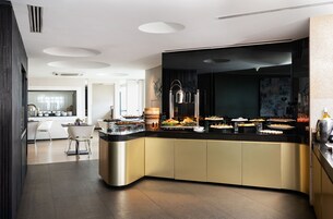 A modern kitchen with a curved island, white chairs, and a dining area.