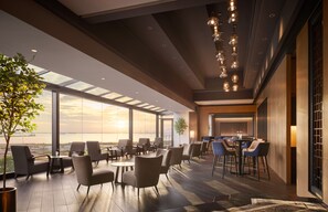 Un moderno vestíbulo de hotel con ventanas amplias, un área de comedor y vistas al atardecer.