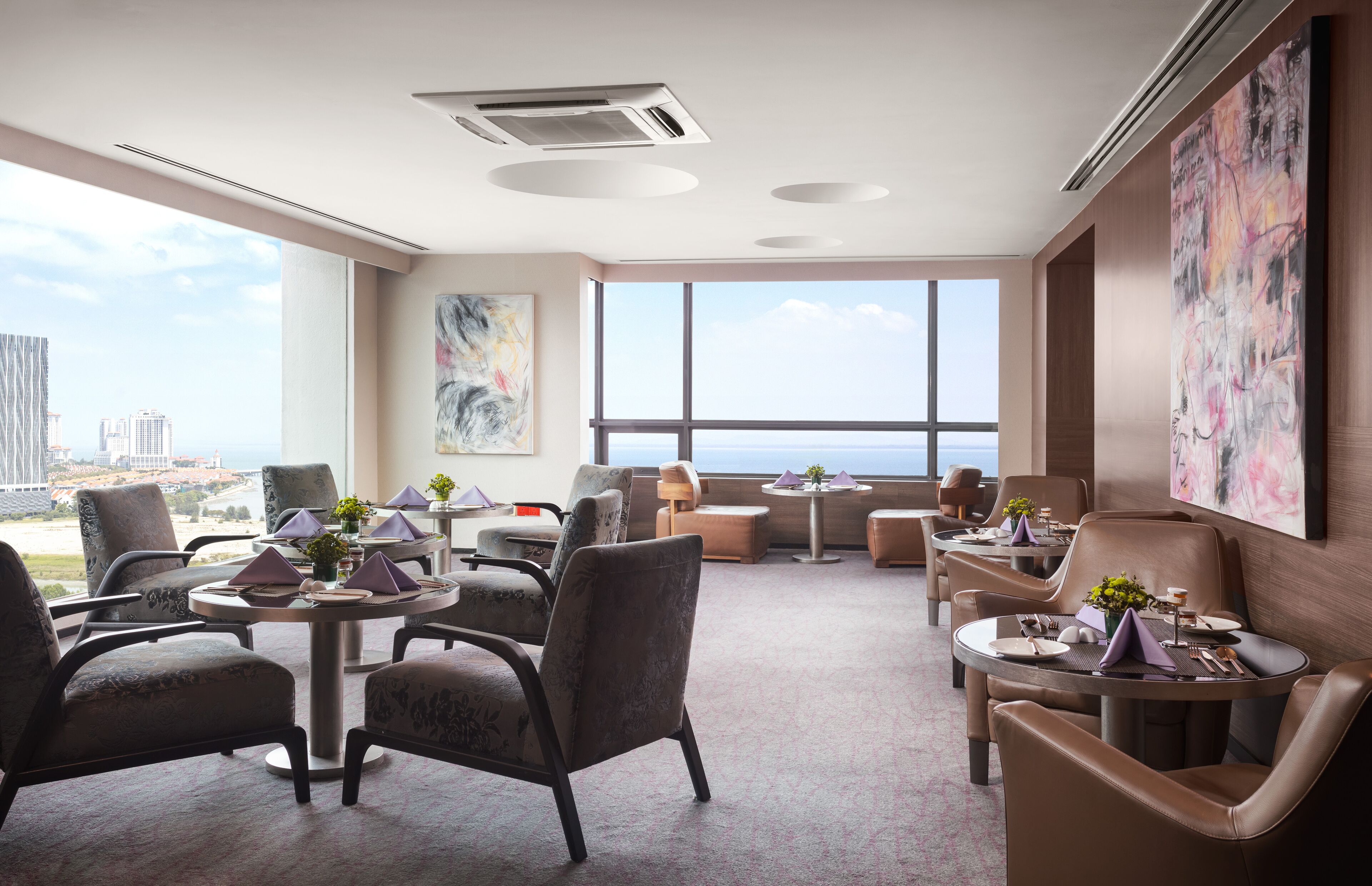Un moderno vestíbulo de hotel con techos altos, ventanas amplias y vistas panorámicas de la ciudad.