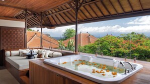 A modern bathroom with a large bathtub, wooden flooring, and a view of the cityscape. - Sadara Resort (Nusa Dua)