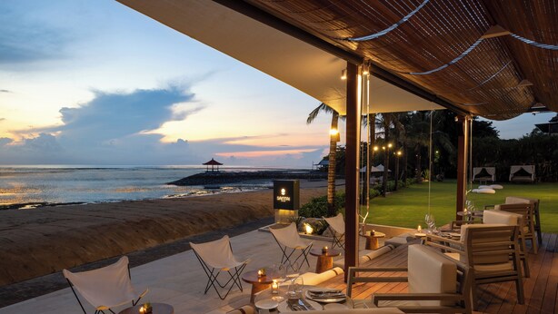 An outdoor dining area with a view of the beach and ocean at sunset. - Sadara Resort (Nusa Dua)