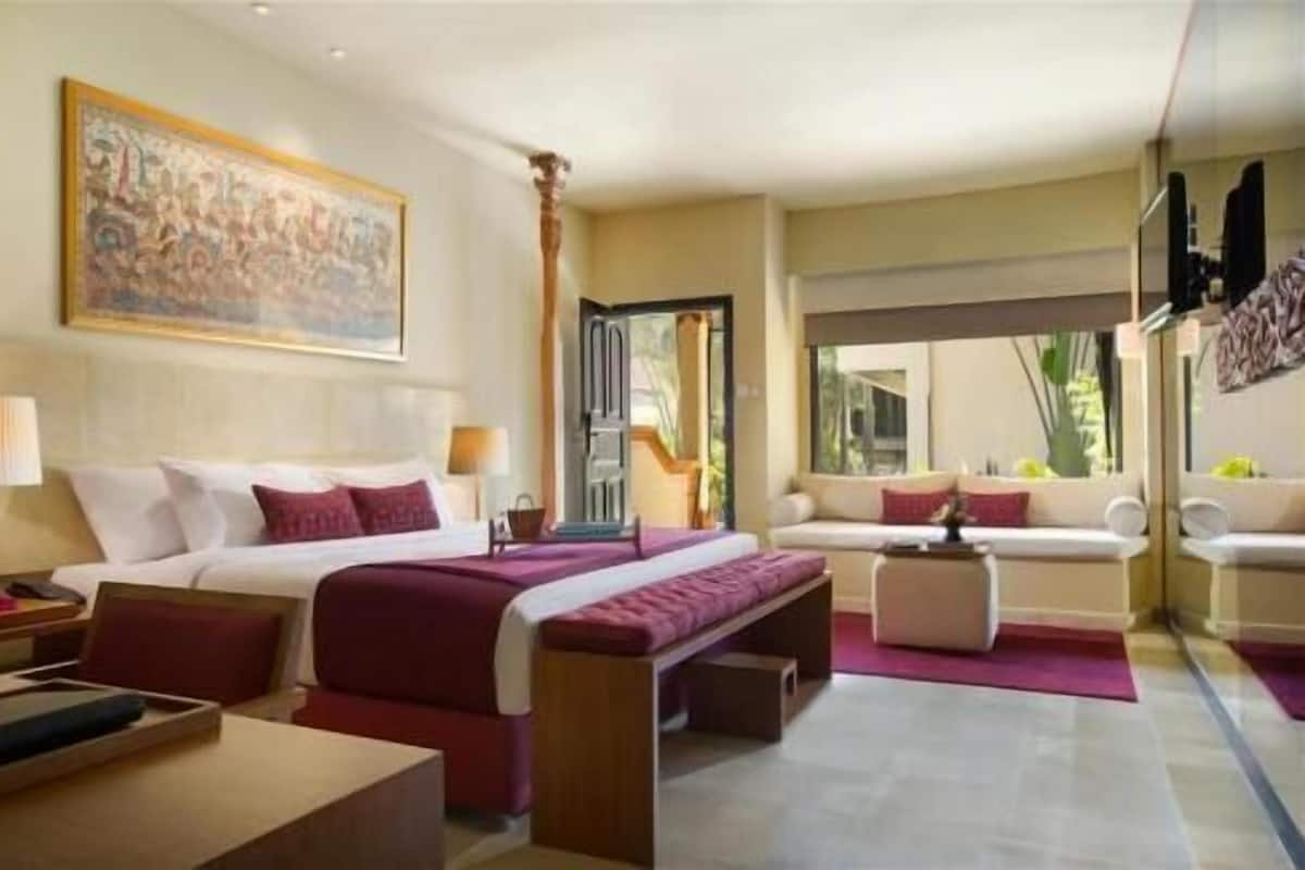 A hotel room with a bed, a sofa, a desk, and a large window.