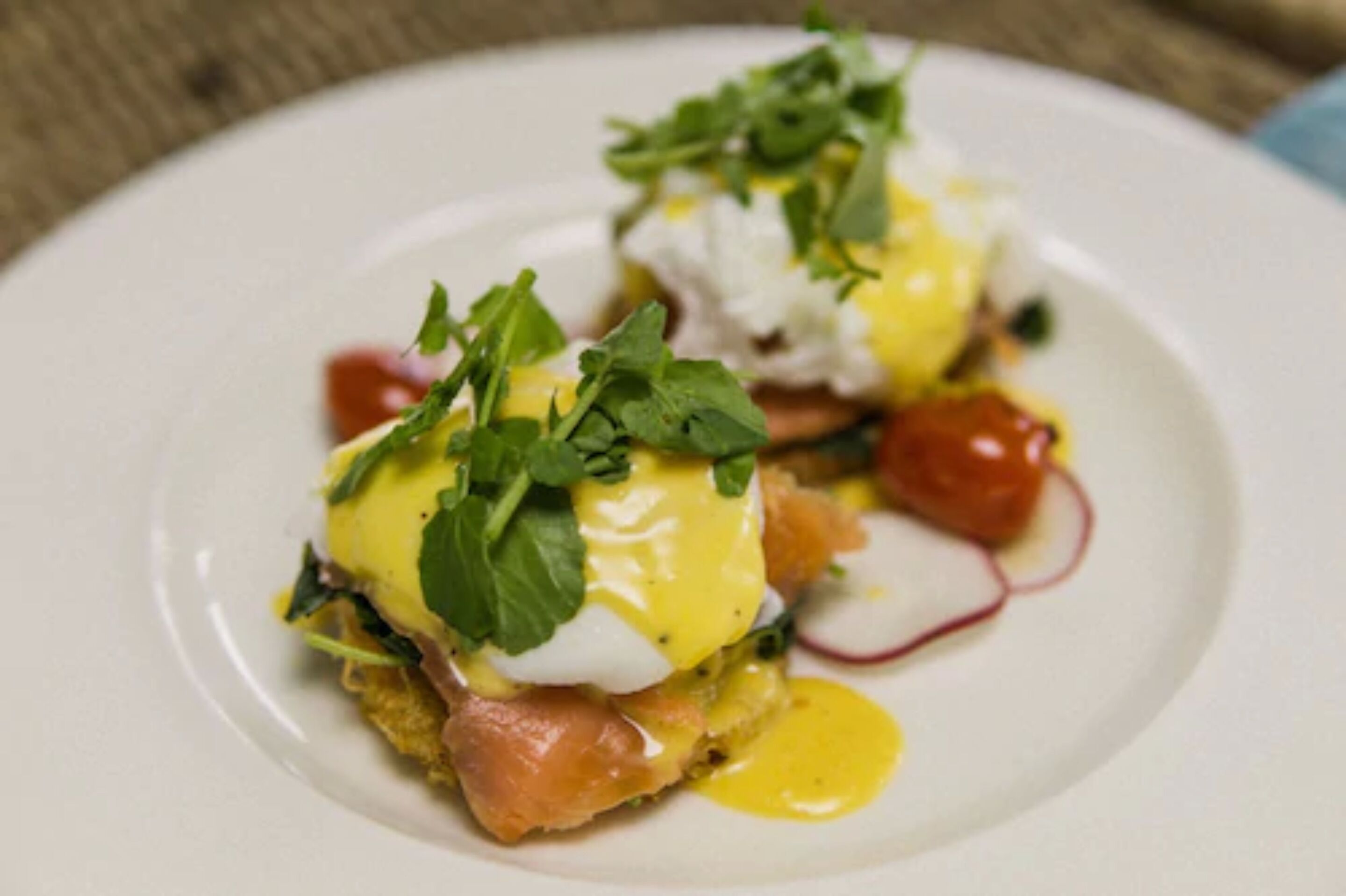 A plate with a dish that includes poached eggs, greens, and a sauce.
