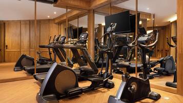 Un gimnasio con varias máquinas de ejercicio, paredes de madera y un espejo grande.